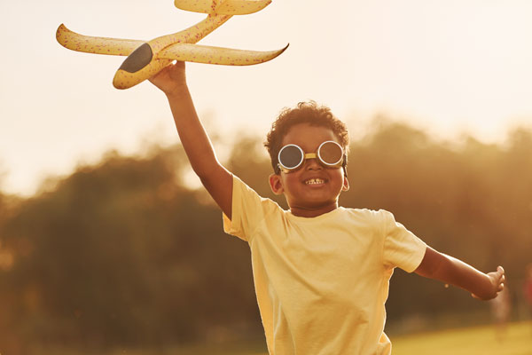 Young African American Boy Flying Toy Airplane through the sky