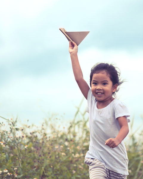 Young girl flying paper airplane