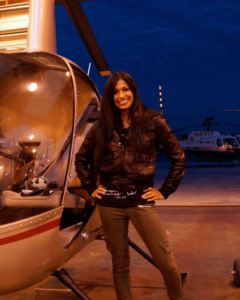 Woman pilot standing next to helicopter